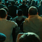 Sitting people watching football in a public place at night